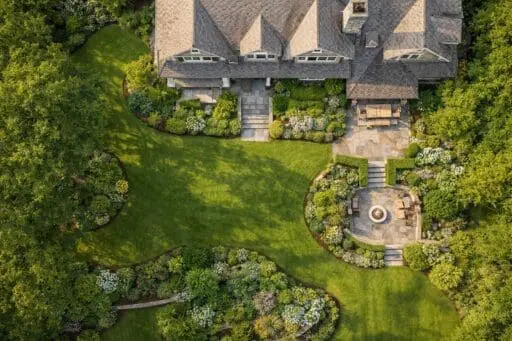 Aerial view of a lush New England estate landscape with layered planting, stone terraces, and timeless outdoor structure.