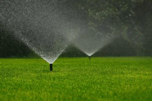 Lawn irrigation system with multiple sprinklers watering a healthy green landscape. abladeofgrass.com