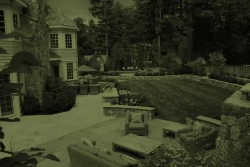 Wellesley, MA - A thoughtfully designed landscape with stone terraces, lawn, layered plantings, and inviting outdoor living spaces.