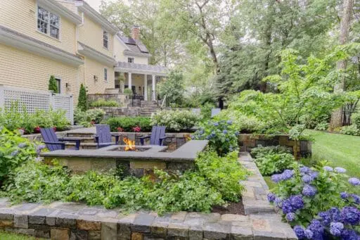 Wellesley, MA - A natural stone fire feature anchors this lower terrace, where hydrangeas, layered perennials, and masonry walls shape a comfortable gathering space. photo credit: Michael J Lee