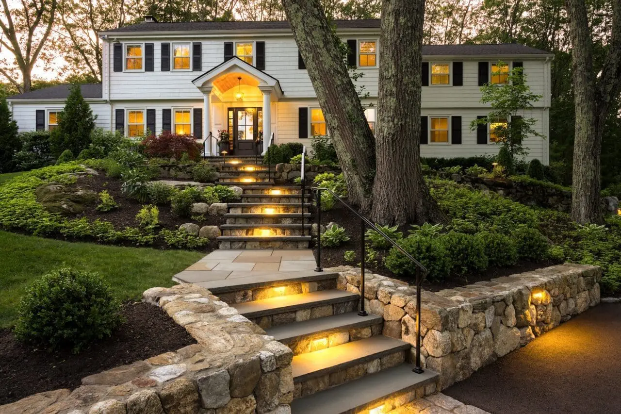 Integrated step and landscape lighting enhances safety, highlights natural stone details, and creates a warm, welcoming approach that makes the landscape as functional at night as it is during the day.