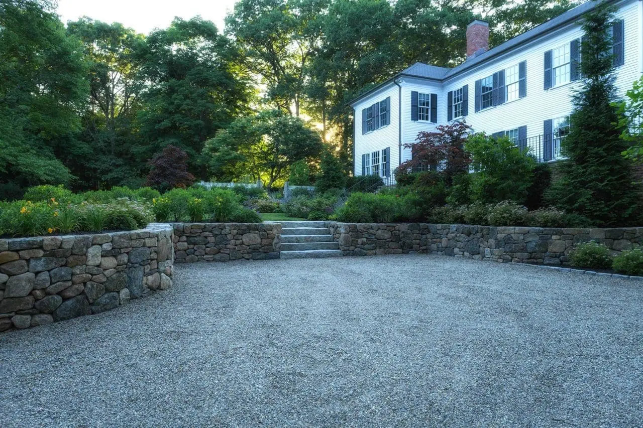 Lincoln, MA - An expertly crafed round fieldstone wall contains this chipseal stone parking court.