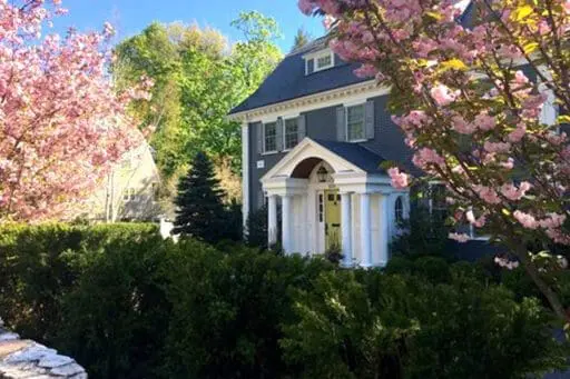 A classic Wellesley home framed by flowering trees, clipped hedges, and lush spring landscaping.
