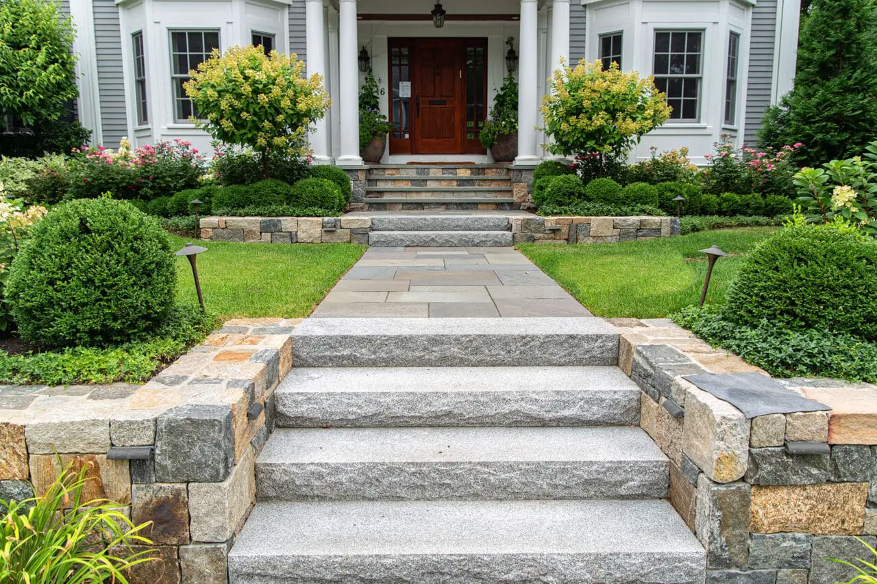 Formal granite steps and cut stone walls define a stately, symmetrical entry suited to Wellesley estates.