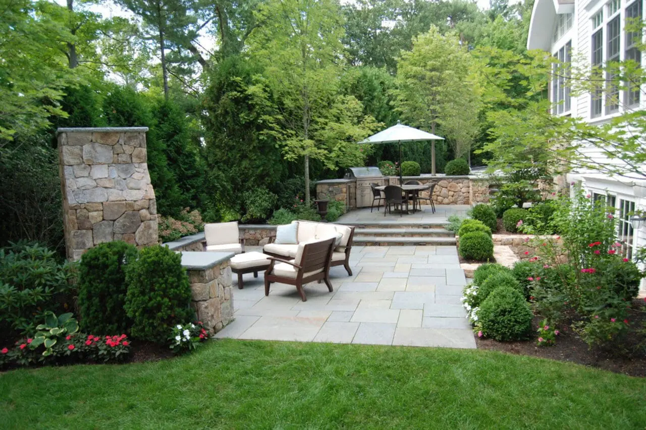 Backyard terrace with outdoor kitchen and fireplace on multiple levels blends cooking, dining, and lounging with seamless stone design for year‑round enjoyment.