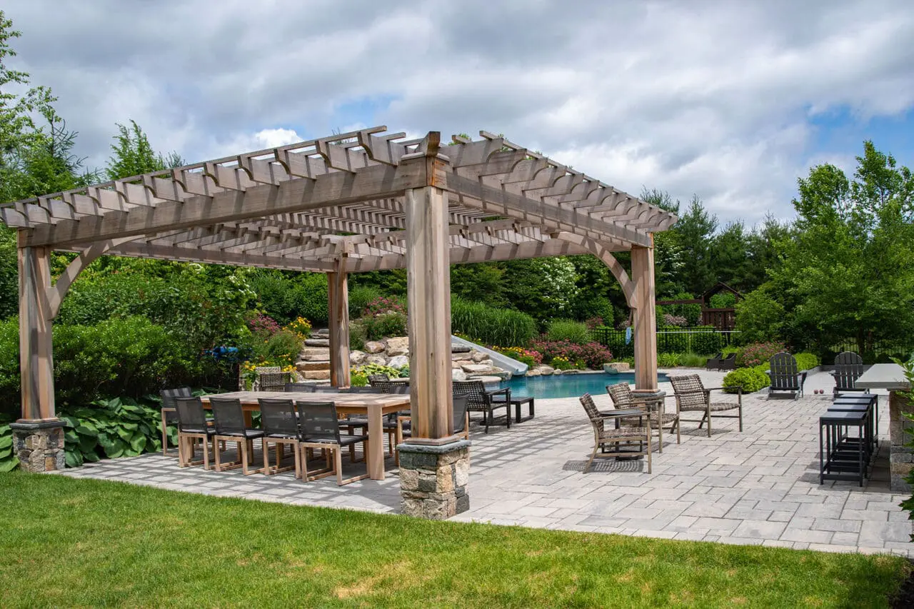 Cedar pergola shelters outdoor dining near the pool, improving comfort and creating a cohesive entertaining zone.