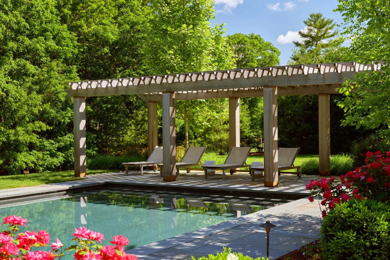 Pergola frames a bluestone pool patio, offering shade and spatial definition while preserving open views and natural light.