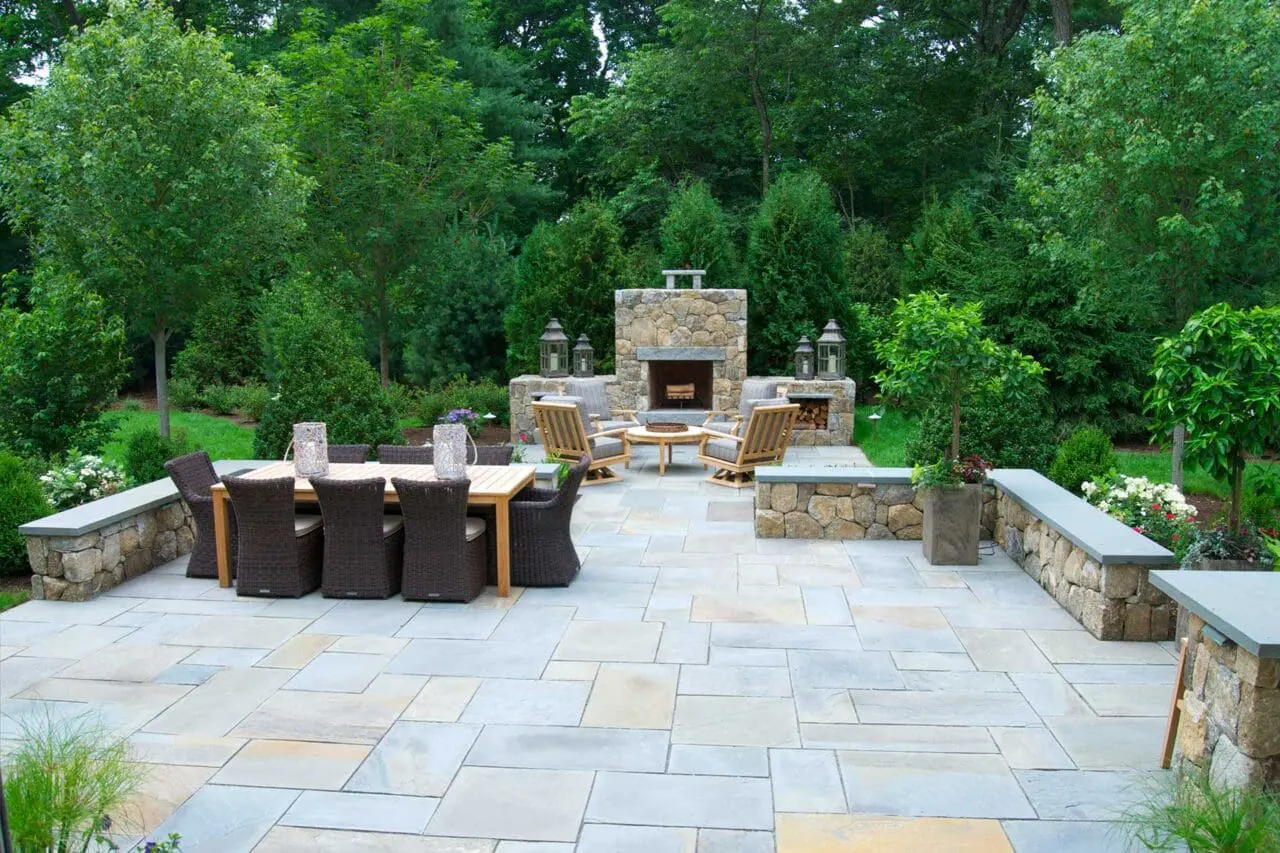 Evergreen plantings paired with masonry elements enclose this fireplace area, creating privacy and shelter for outdoor gatherings.