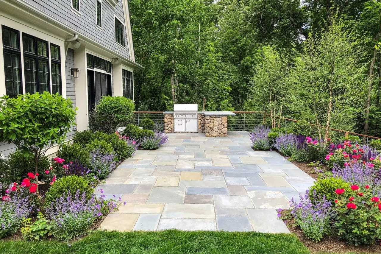 Lincoln, MA - After the transformation, this Weston patio becomes a polished outdoor living space with refined stonework, comfortable furnishings, and layered planting that gives the area structure and privacy.