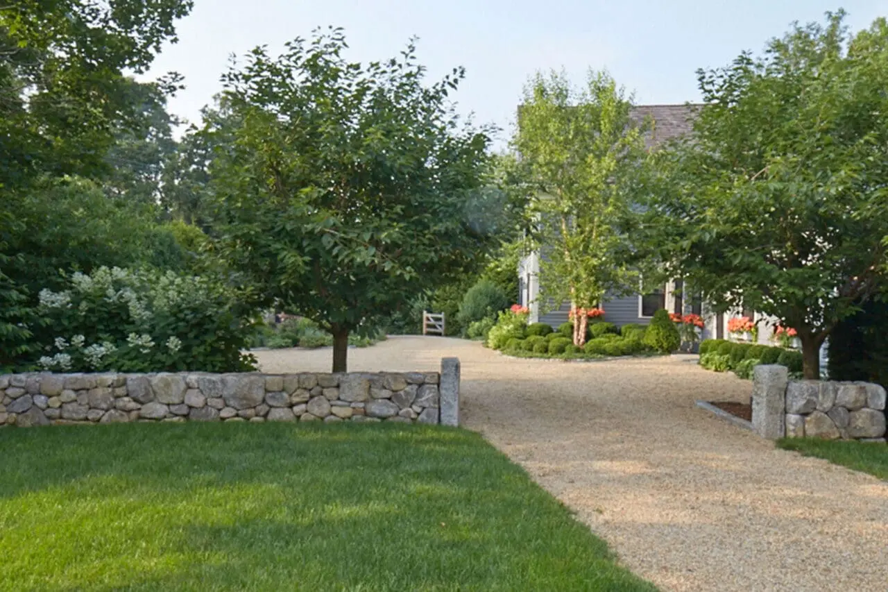 Wayland, MA - A fieldstone wall lines the driveway entry, using natural stone mass to define the approach and frame the gravel drive. © charles mayer photography