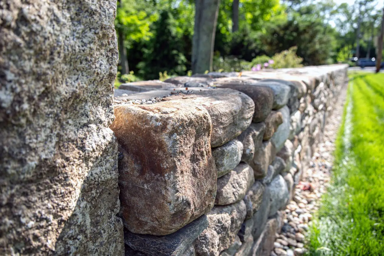 A fieldstone retaining wall manages the hillside grade, with granite steps providing a durable and clearly defined path through the slope.