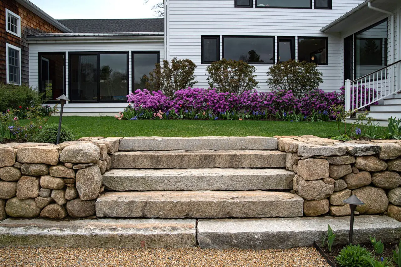 Carlisle, MA - These granite steps are set into fieldstone walls near the foundation, where carefully scaled shrubs and hedges help transition between architecture and landscape.