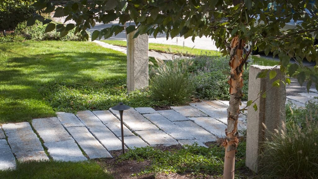 A gently curving stone path leads through layered garden plantings, showing how circulation can feel natural while still giving the landscape clear structure.