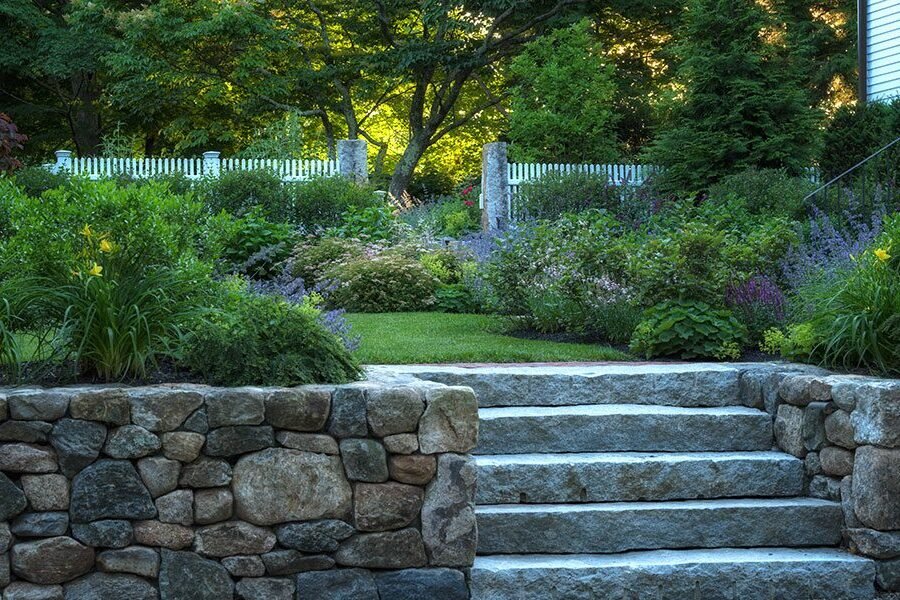 Reclaimed granite steps and fieldstone walls give this lush garden a beautifully settled, timeworn character.