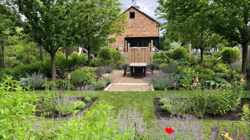 Carlisle, MA - A garden setting with native plantings surrounding a simple barn structure, creating a functional outdoor space that blends naturally with its surroundings.
