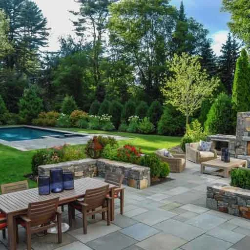 Dover, MA - This stone patio creates an inviting backyard gathering space with natural masonry, layered planting, and timeless residential landscape design.