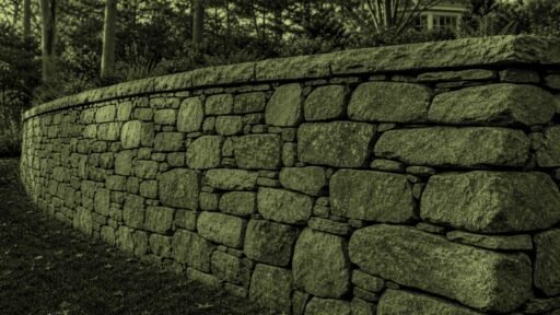 Acton, MA - A stone retaining wall leans outward, indicating movement and possible structural failure.