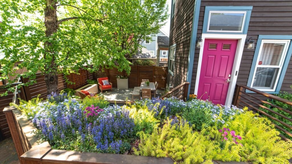 Cambridge roof garden with built-in wood planters, colorful flowering perennials, mature shade trees, and a compact outdoor seating area.