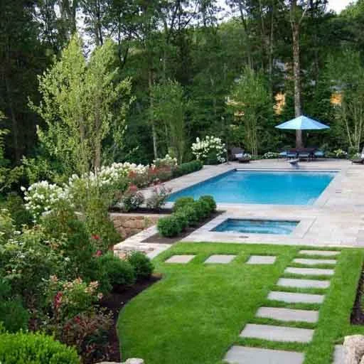 Needham, MA - A rectangular pool with bluestone paving, an integrated spa, and woodland garden planting creates a serene backyard destination.