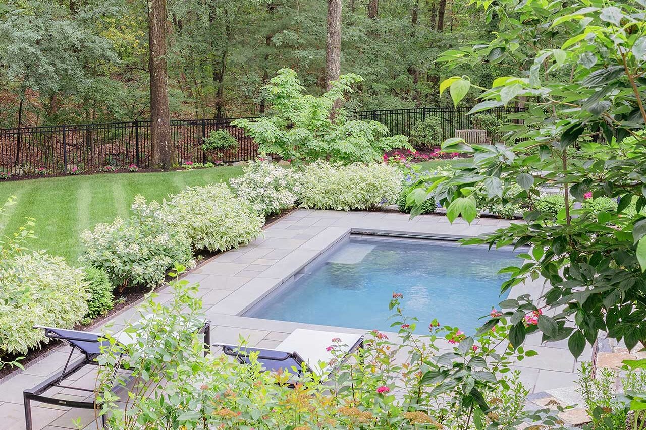 Wellesley, MA - The pool terrace sits comfortably within a framework of flowering shrubs, clipped evergreens, and mature woodland, balancing openness with privacy. photo credit: Michael J Lee