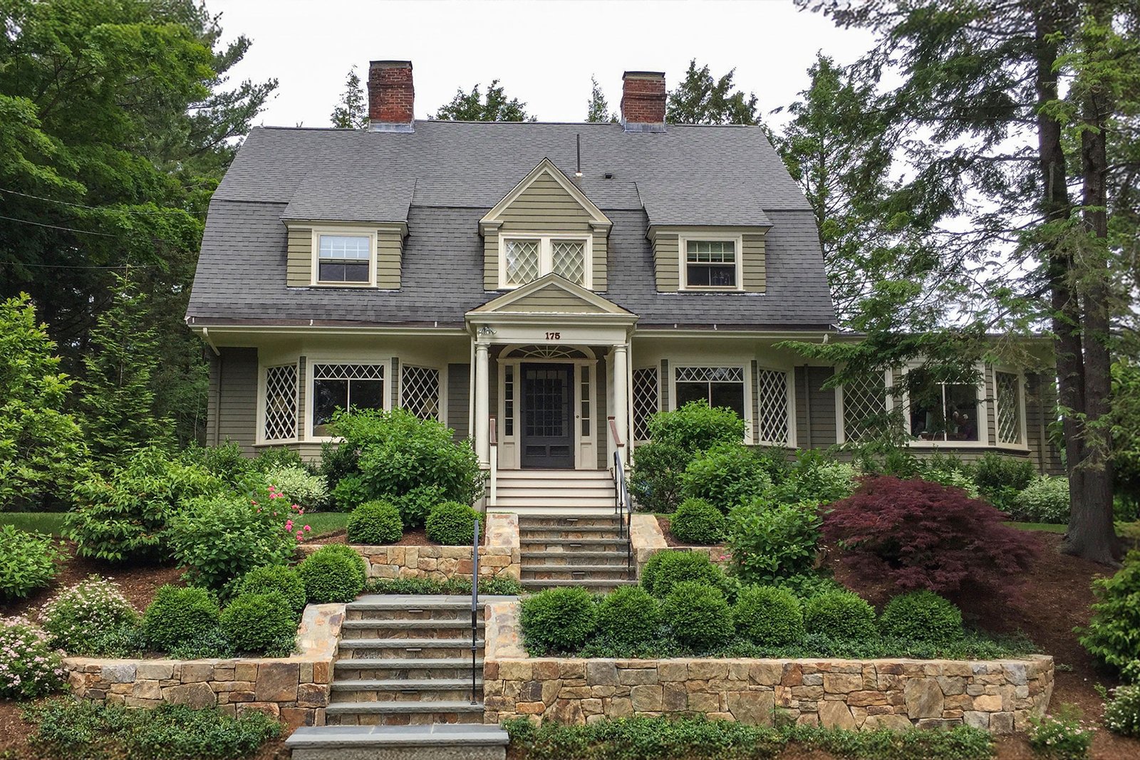 Newton front yard with stone terraces and layered foundation planting