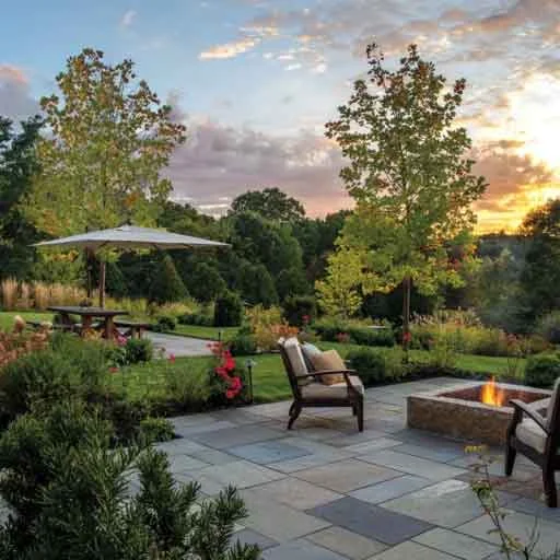 Weston, MA - This charming fire pit patio combines rugged stonework, open sunset views, and comfortable seating for a distinctive outdoor entertaining space.