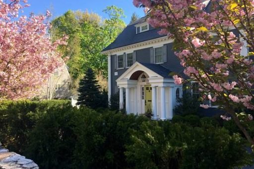 Flowering trees and clipped evergreens frame a classic Wellesley entry, creating a polished arrival with strong spring color and year-round structure.