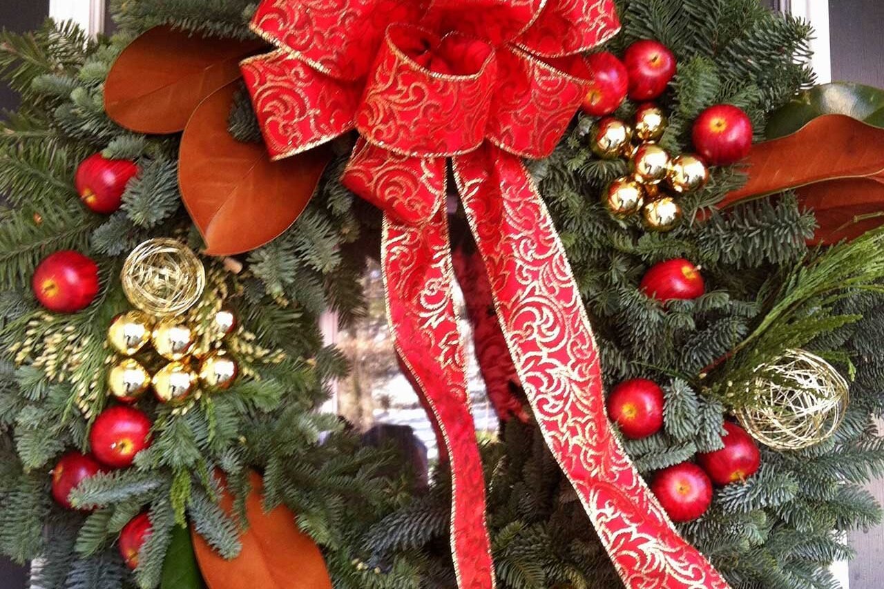 Red and gold accents bring warmth and contrast to this evergreen wreath, offering a refined take on traditional holiday colors.
