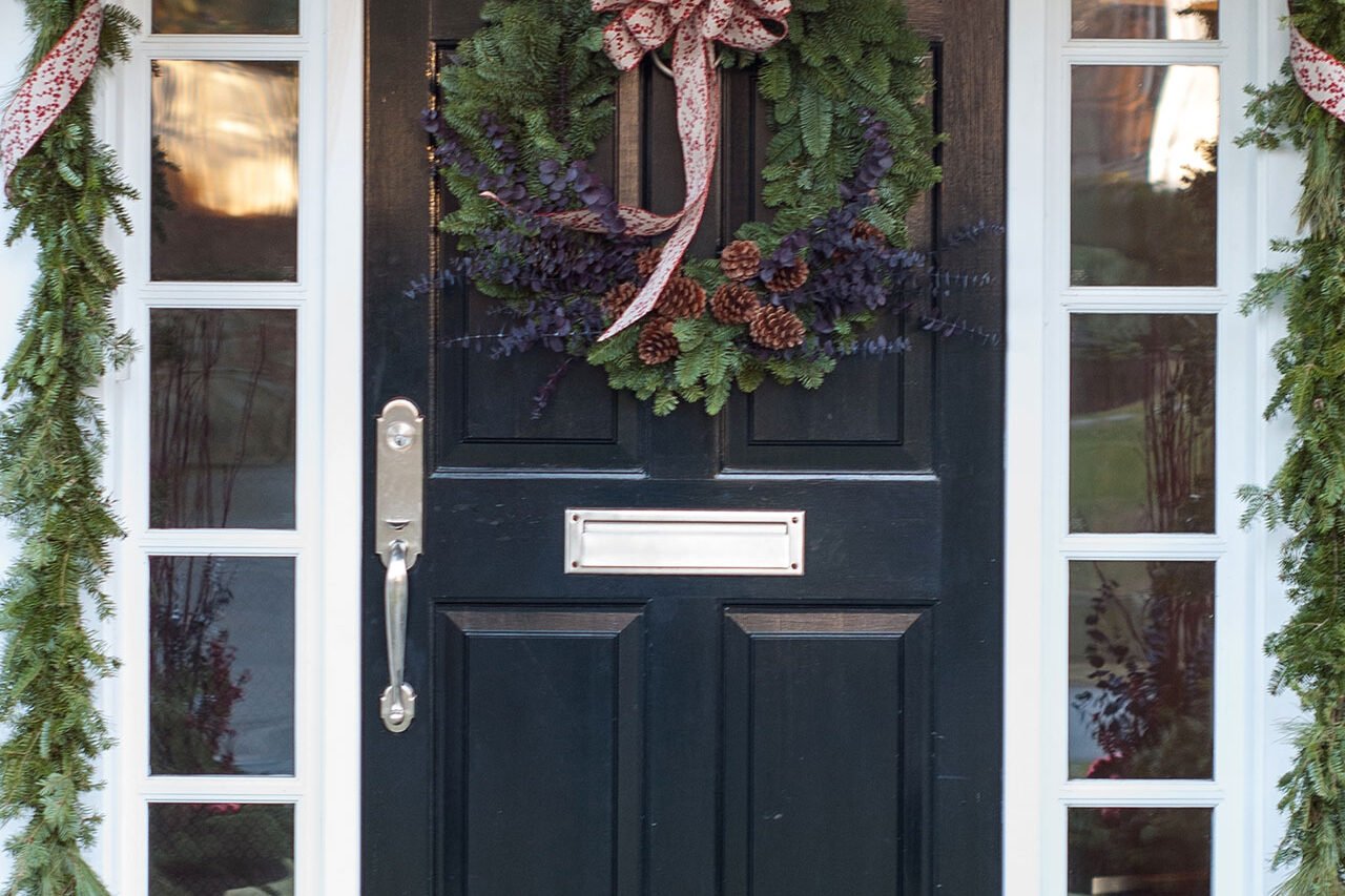 Wreath and garland work together to frame the door, creating a cohesive holiday look rooted in New England tradition.