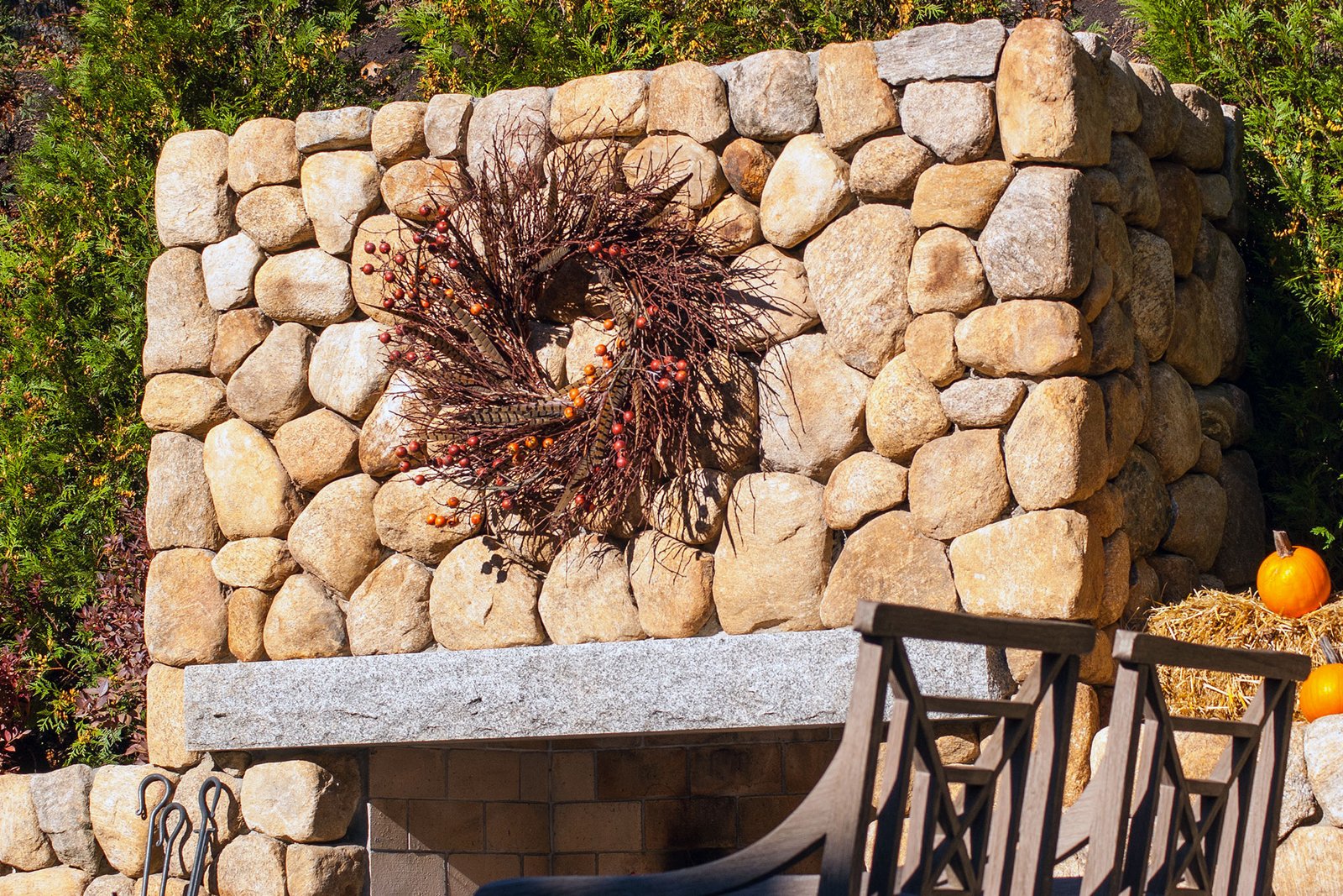 A natural branch wreath brings texture and earthy tones to fall displays, echoing the warmth of stone walls and masonry details.