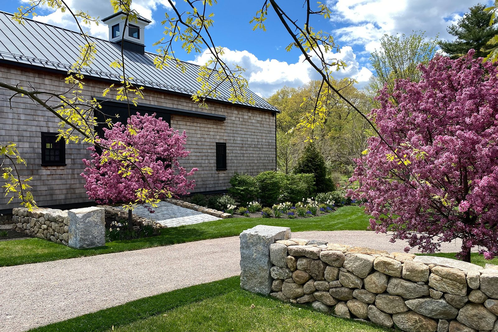 Carlisle, MA - Stone edging defines this curved gravel driveway, working with layered foundation plantings to blend hardscape and landscape into a cohesive entry sequence.