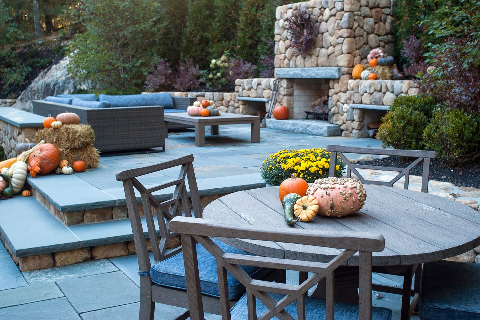 Weston, MA - Bluestone patio decorated with pumpkins near an outdoor fireplace creates a warm harvest setting for fall gatherings and entertaining.
