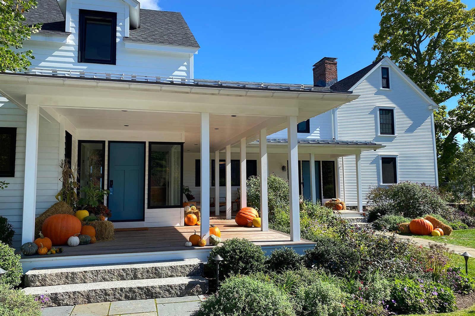 Carlisle, MA - A modern farmhouse porch styled with pumpkins and hay bales creates a warm, welcoming entry, blending rustic materials with playful fall flair and plenty of design flexibility.