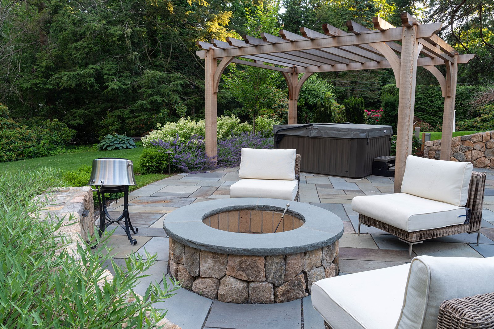 This round masonry fire pit is integrated into a cedar pergola and spa terrace, creating a cohesive outdoor retreat that balances warmth, relaxation, and architectural structure.
