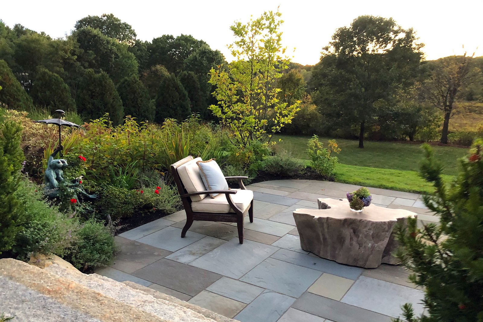 A sculptural accent integrated into a bluestone patio seating area adds texture and visual interest, subtly defining the outdoor gathering space.