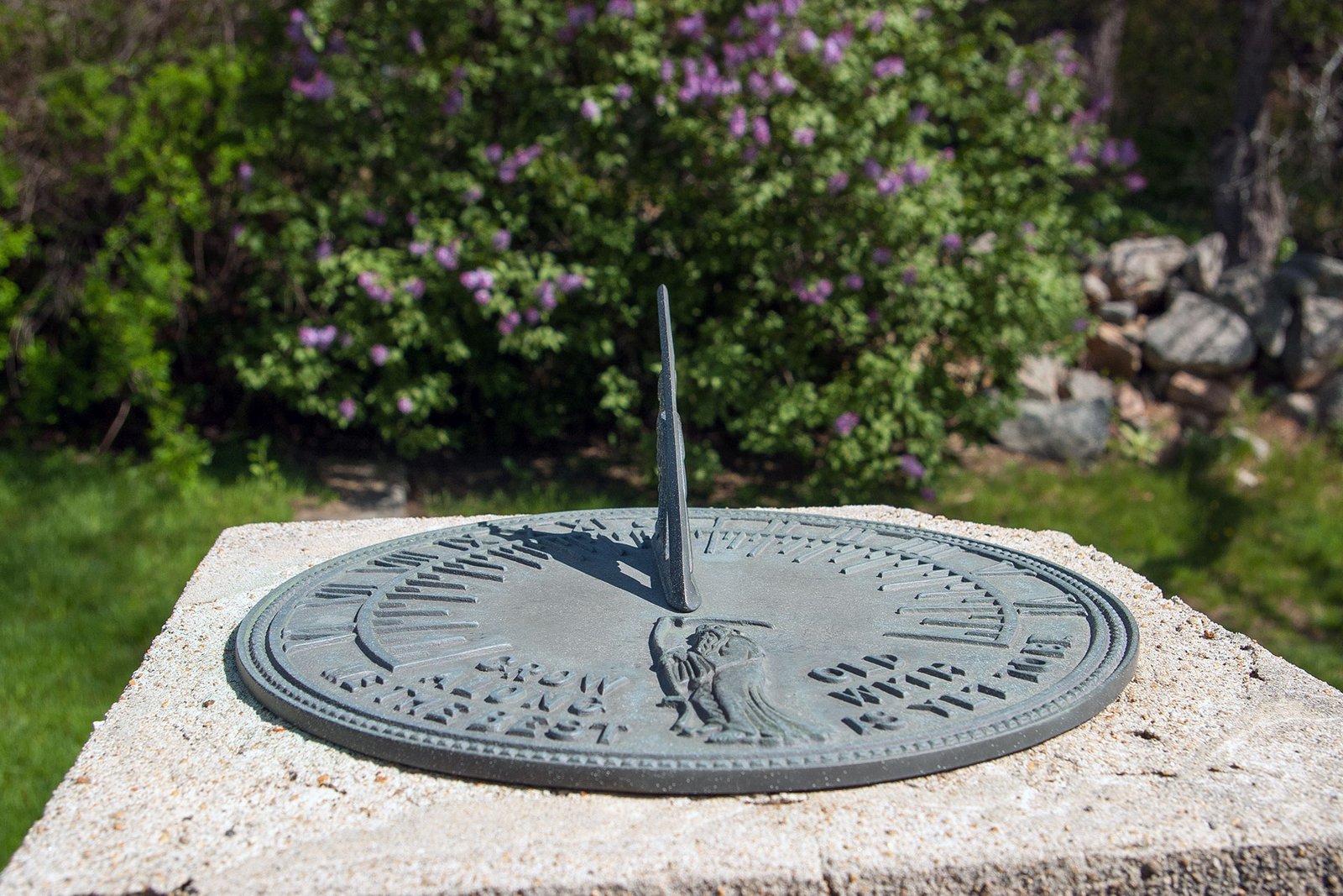 A cast metal sundial mounted on a stone pedestal introduces timeless symbolism, blending utility and ornament as a refined garden detail.
