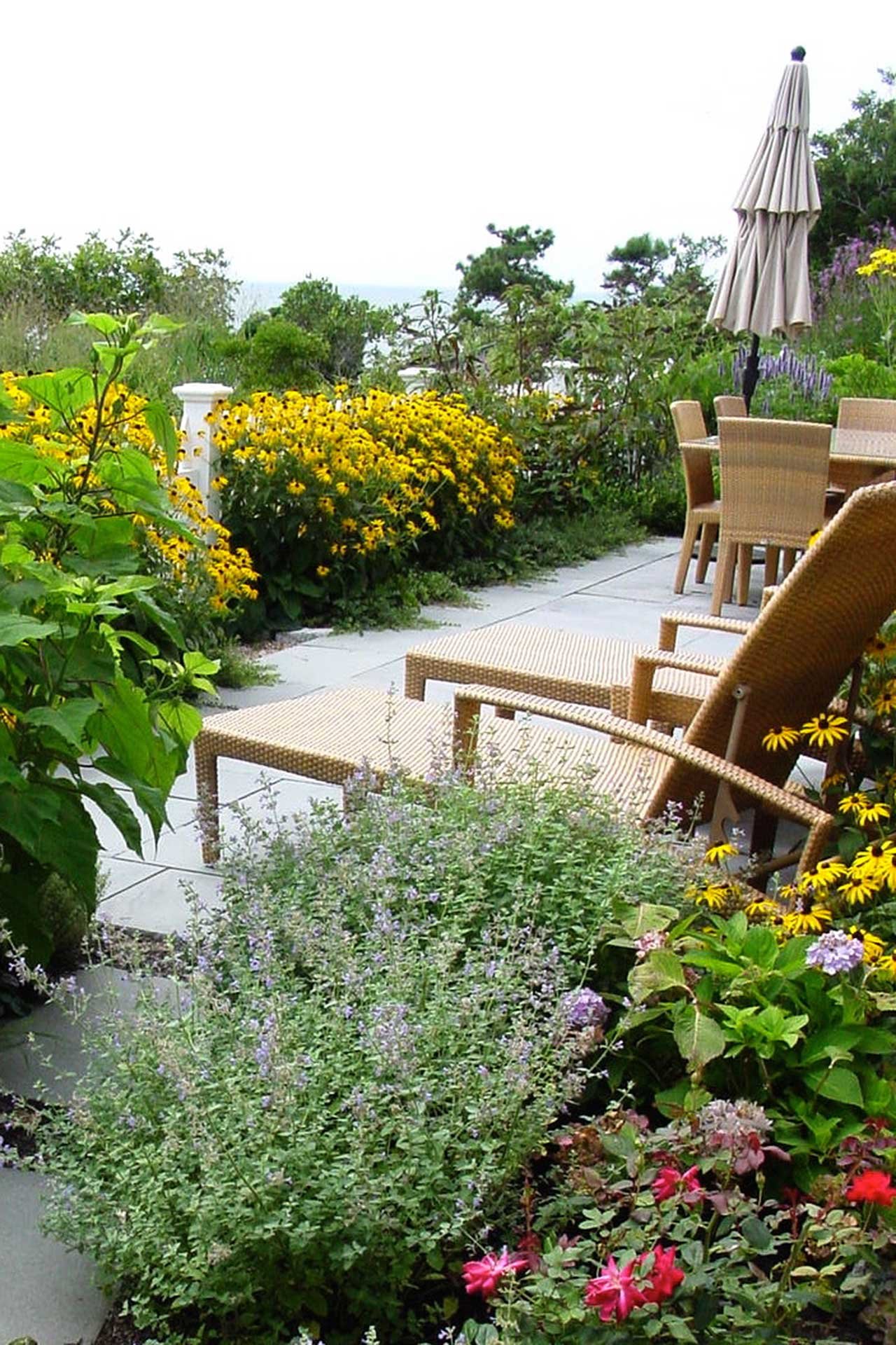 Well-maintained perennial plantings frame the bluestone patio, reflecting attentive seasonal care and ongoing garden stewardship.
