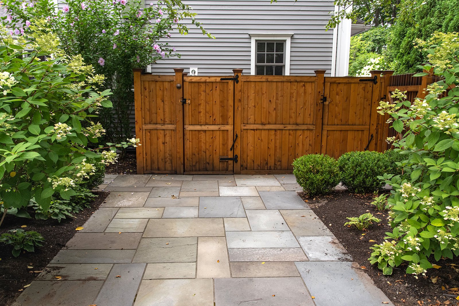 This cedar board fence and gate screens a bluestone patio, enhancing privacy while maintaining a cohesive material palette.