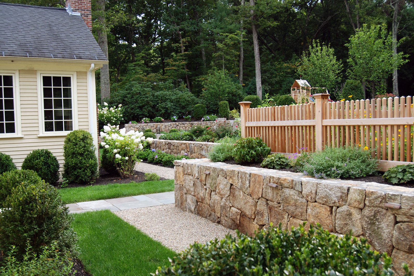 Cedar pickets paired with stone walls provide warmth and structure, helping garden beds feel intentional and contained.