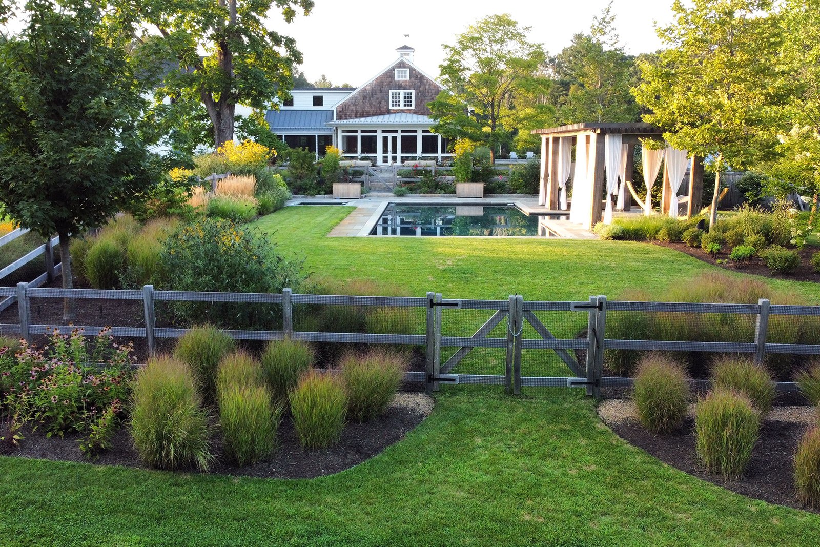 A low-profile wood fence in Carlisle, MA organizes the garden boundary, protecting beds and guiding movement without closing off the landscape.