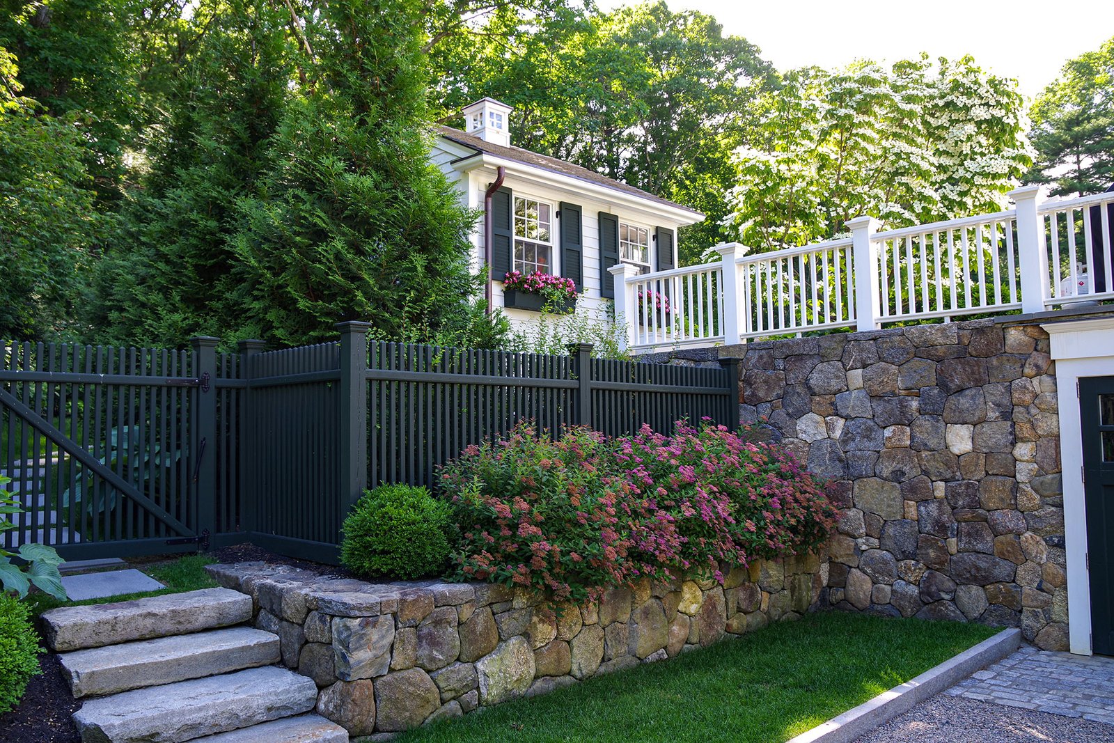 Layered fencing atop a stone wall addresses elevation changes, reinforcing privacy and safety while keeping the landscape organized.