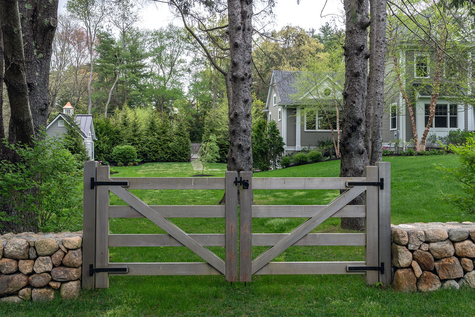 A gray wood gate paired with fieldstone walls in Weston blends function with heritage, guiding access through the garden.
