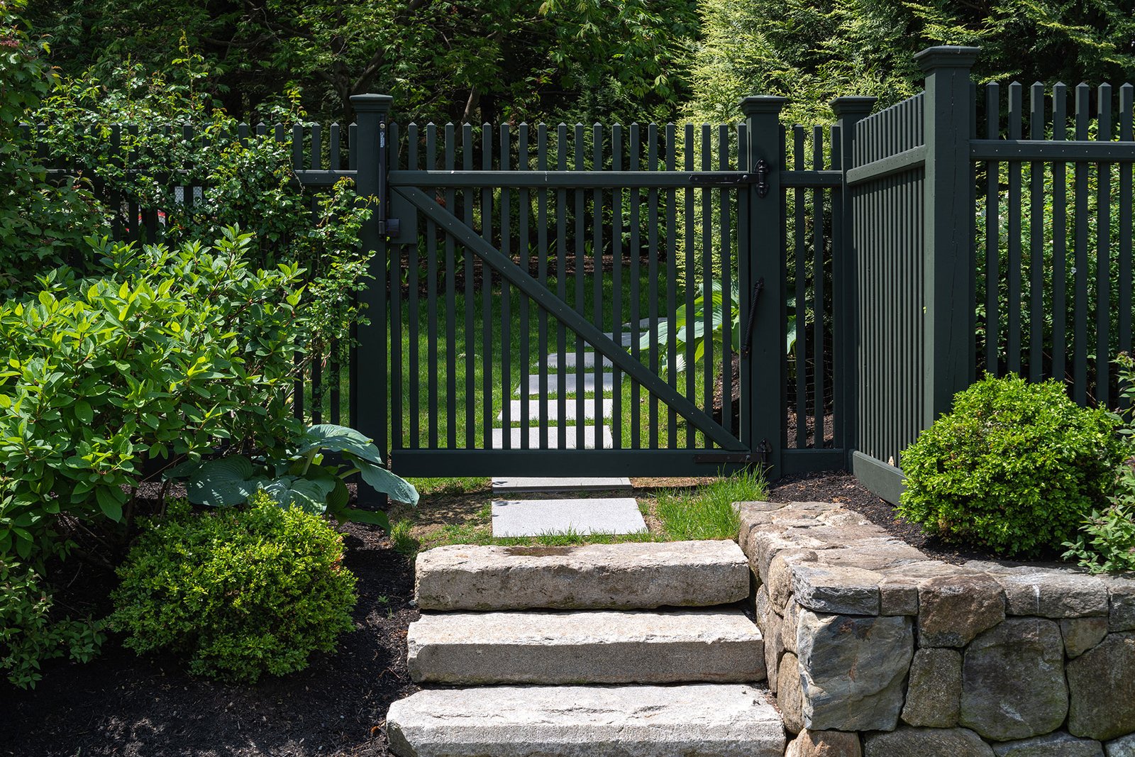 A coordinated wood fence and gate manage entry at the steps, using consistent tones to visually organize the transition between levels.