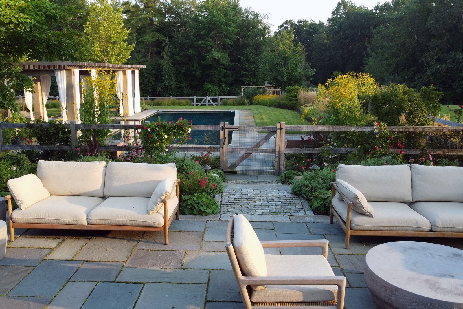 Natural wood pool fencing blends with native plantings, creating a safe enclosure that protects children and pets without interrupting the Carlisle backyard views.