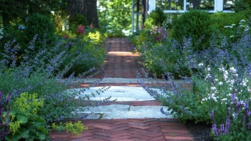 Lincoln, MA - An antique granite millstone pulls your attention in while nepeta, alchemilla, and salvia perennials gracefully soften the herrgingbone pattern walkway.