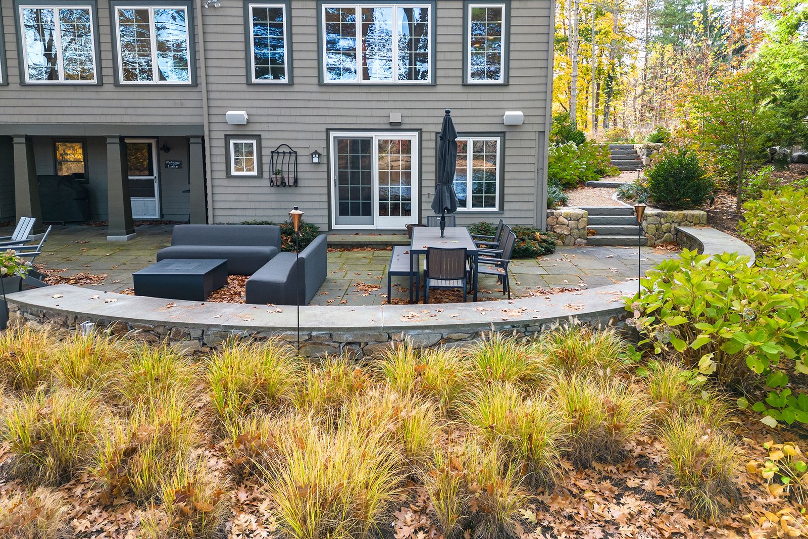 Ornamental grasses line the curved driveway edge, adding soft texture and seasonal color while reinforcing structure and visibility. The flowing border elevates curb appeal at this Weston home.