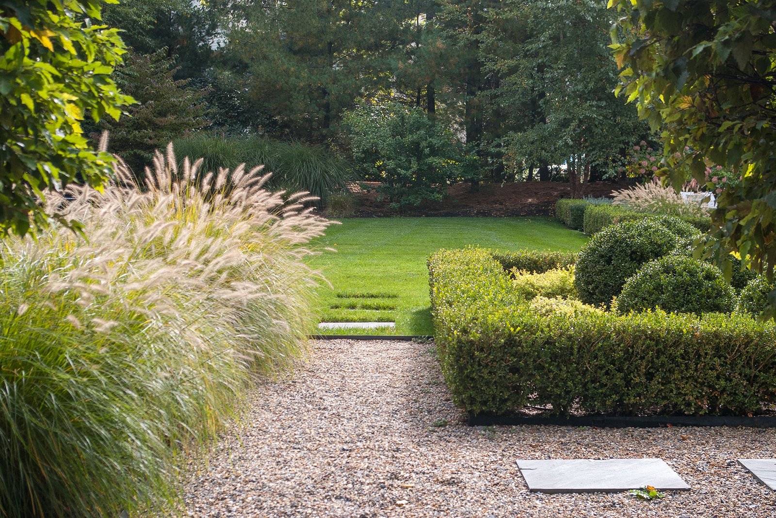 Feather reed grass lines a pea stone path in Lexington, adding texture, movement, and durability while reinforcing a natural garden rhythm.