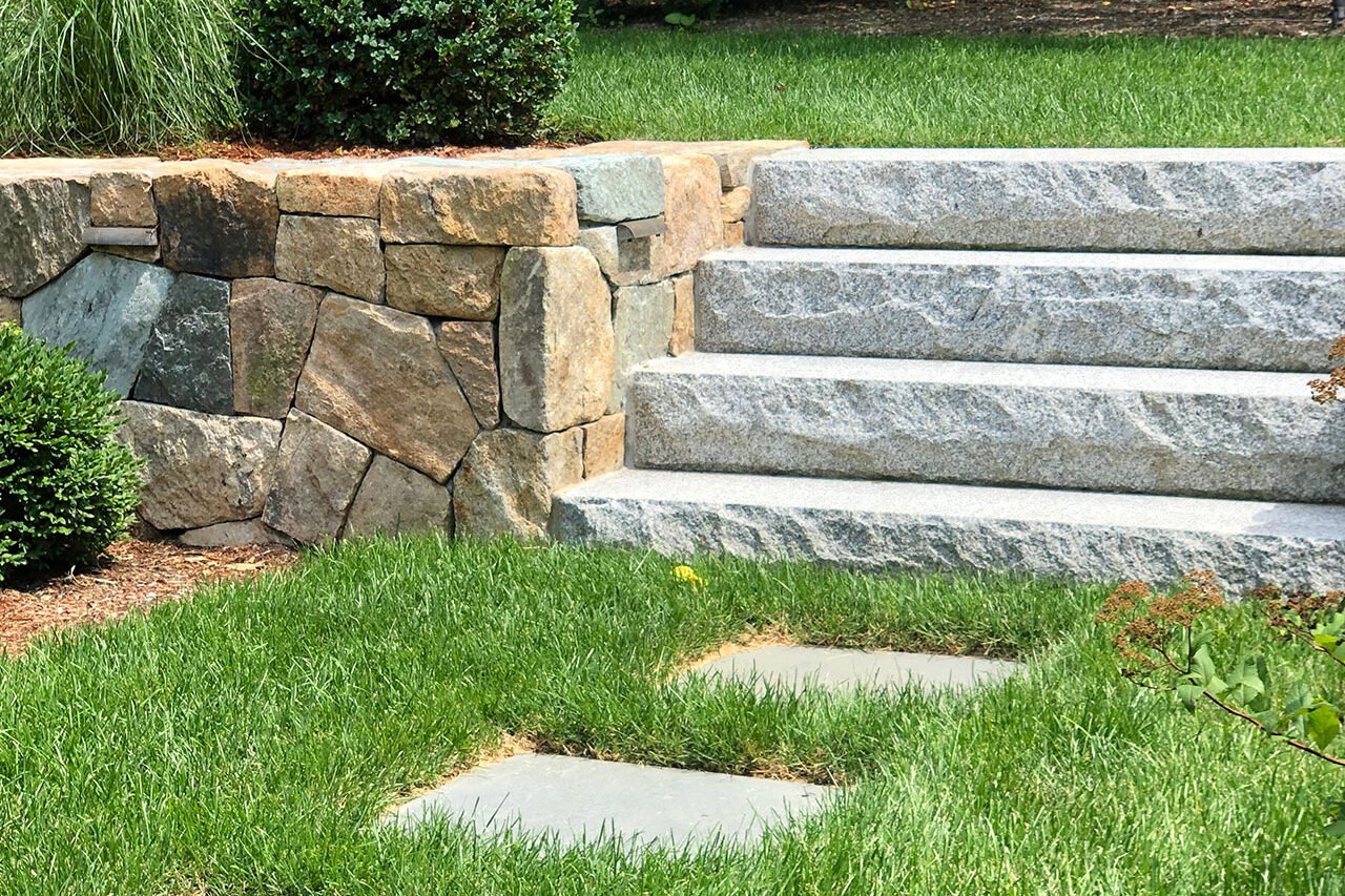 Bluestone and gravel path supports drainage while moving naturally through shade-tolerant planting.
