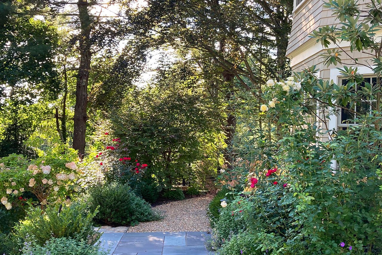 Bluestone walkway transitions to pea stone, softening the formality of the approach while maintaining clear circulation and durable footing through the garden.