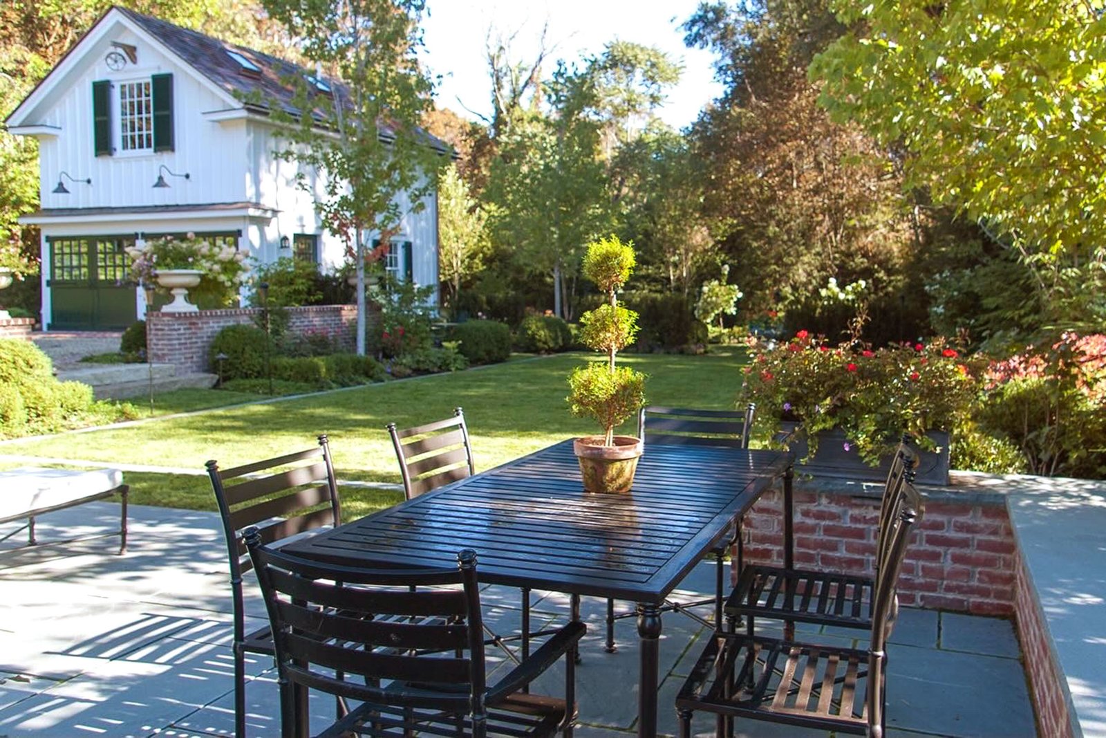Belmont, MA - Classic backyard patio with brick walls and dining table combines traditional hardscape with comfortable outdoor living for family meals and entertaining.